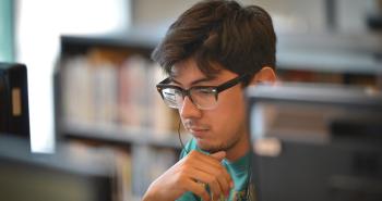 Student with Glasses on Computer