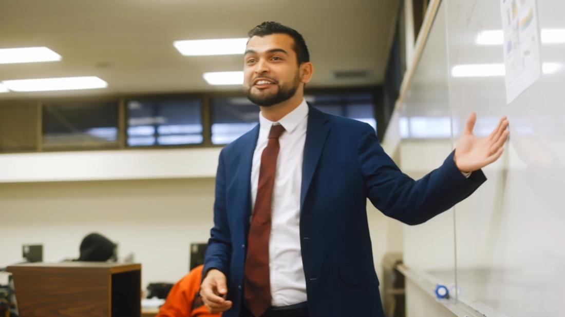 Man in suit gesturing to whiteboard