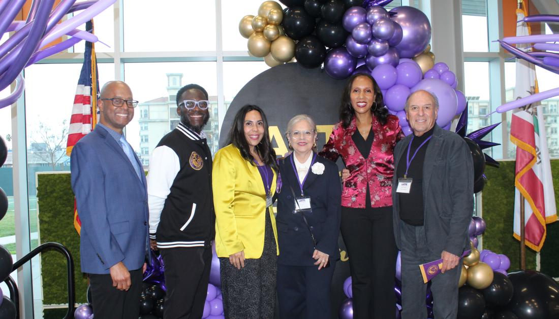 Administrators and alumni smile on stage